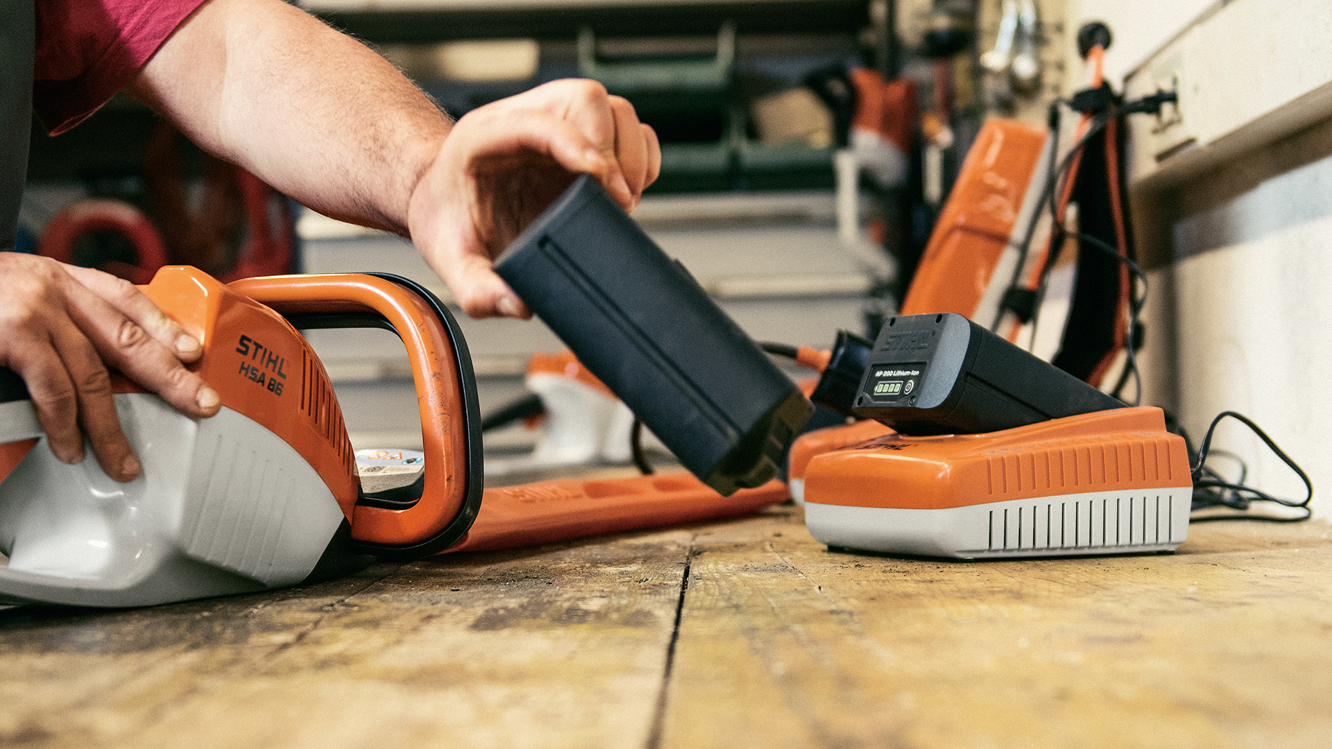Ett STIHL AK -batteri från STIHL AL 300 snabbladdare sätts in i batterihäcksaxen STIHL HSA 86 på en arbetsbänk