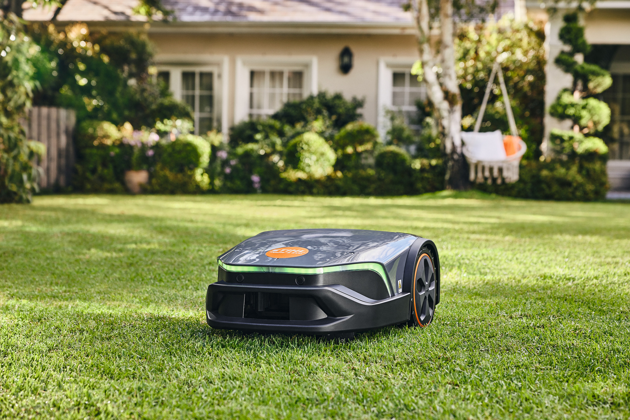 En STIHL iMOW® robotgräsklippare på en grön gräsmatta i en trädgård