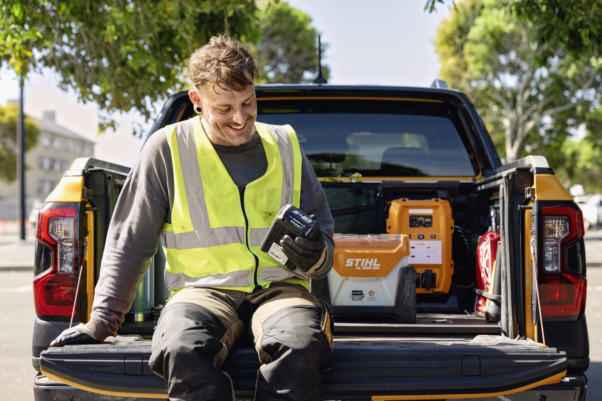 En man i ett förråd med STIHL-verktyg och batterier bär STIHL ADVANCE X-Flex modulära selesystem 
