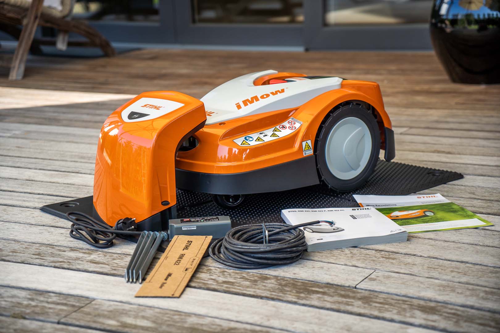 En STIHL iMOW® 422 robotgräsklippare i dockningsstation med slinga och bruksanvisning