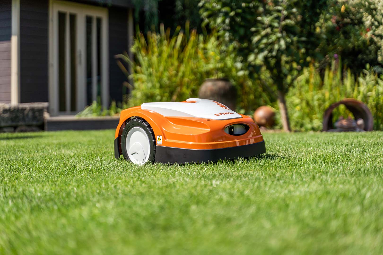 En STIHL iMOW® robotgräsklippare i en trädgård