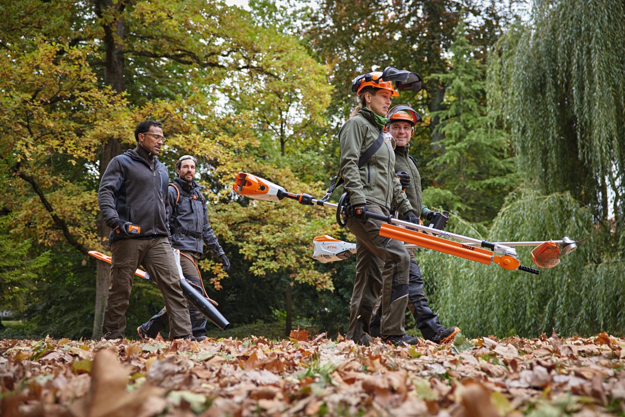 Fyra STIHL-proffs med batteridrivna maskiner som går längs en väg