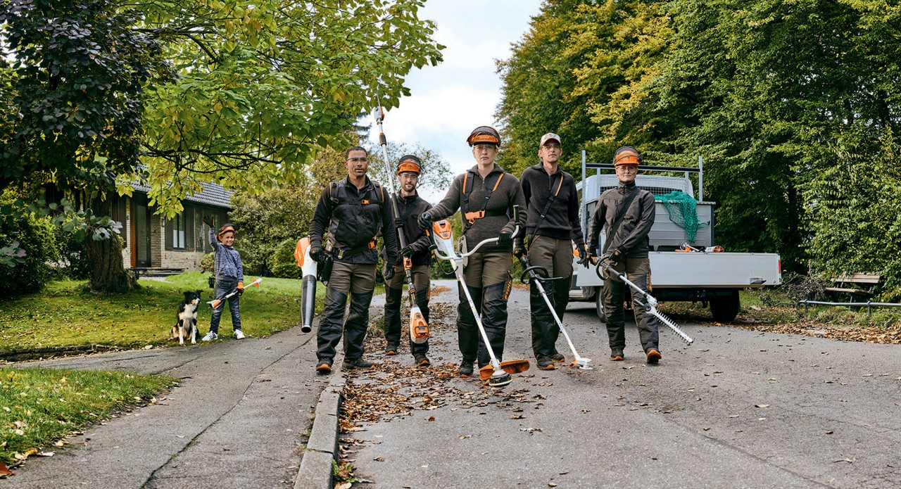 Ett trädgårds- och miljöteam med professionella batteridrivna maskiner från STIHL går längs en gata.
