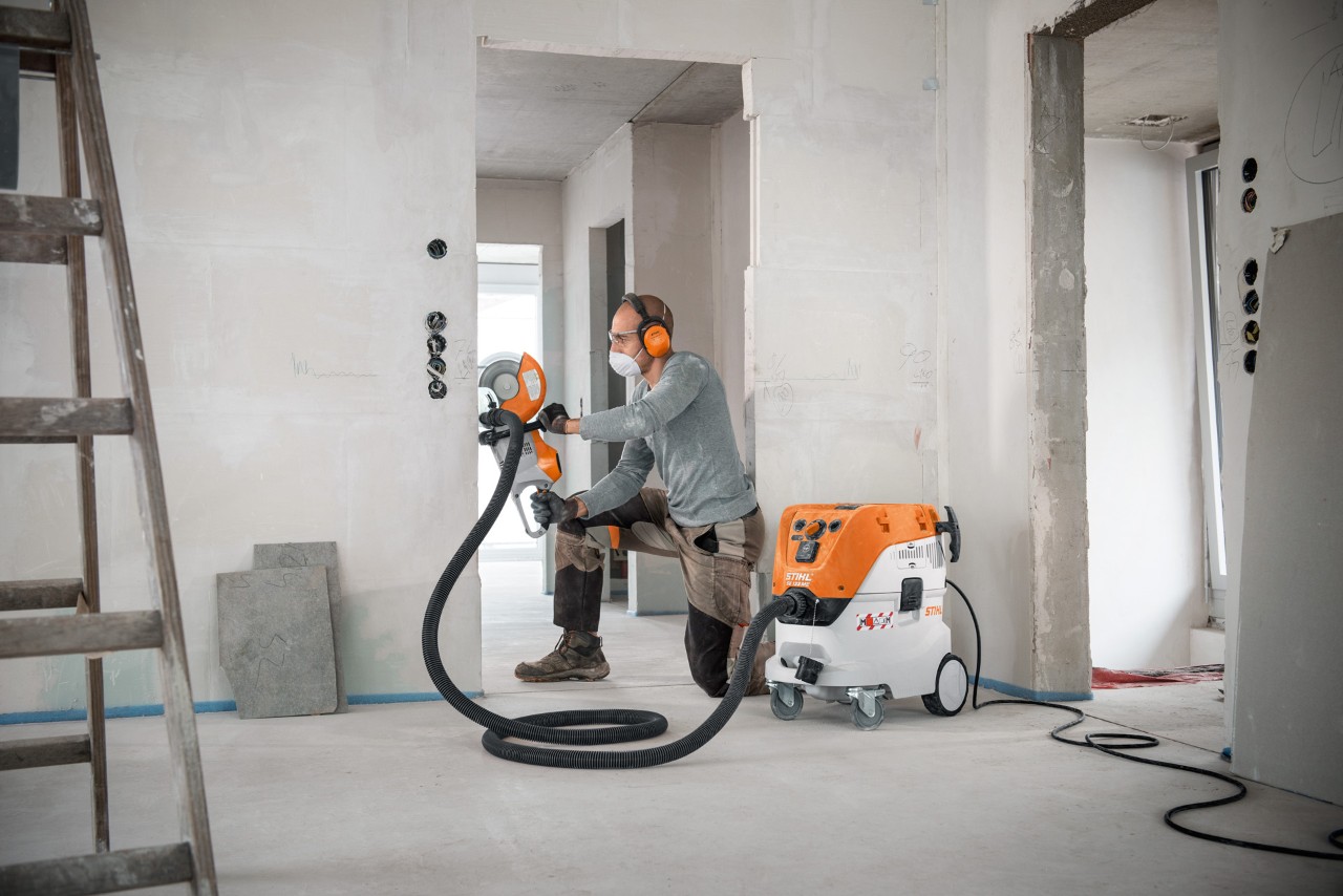 En man som arbetar med en STIHL SE 133 ME våt- och torrdammsugare och en STIHL TSA 230 kapmaskin