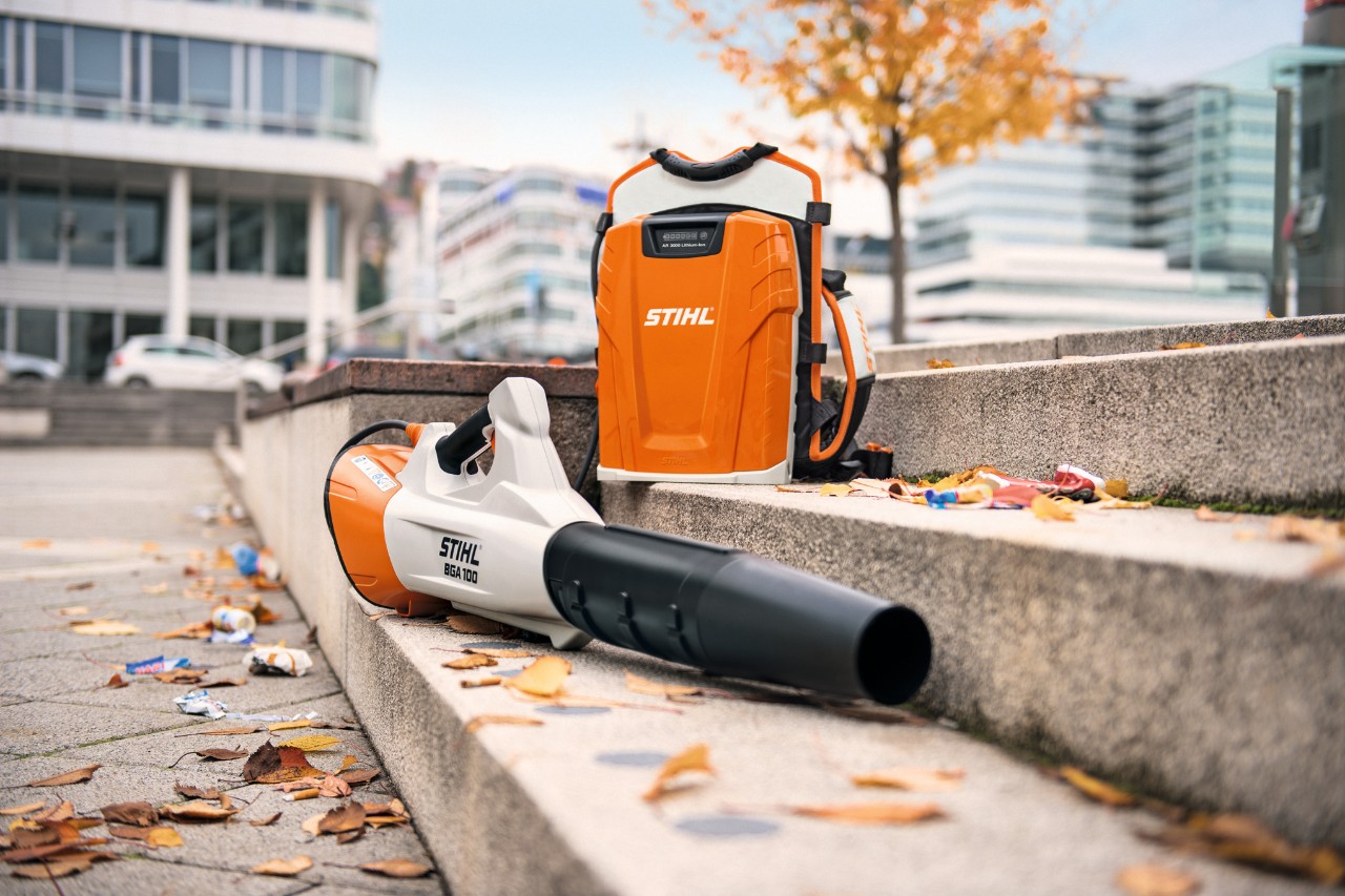 STIHL BGA 100 batteridriven lövblås och STIHL AR 3000 L ryggburet batteri placerade på en stentrappa med några löv