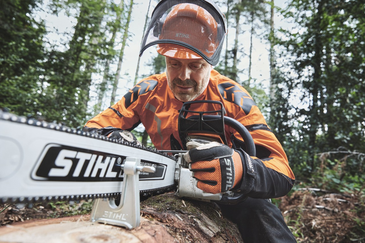 En man i skyddsutrustning arbetar med en STIHL motorsåg i skogen