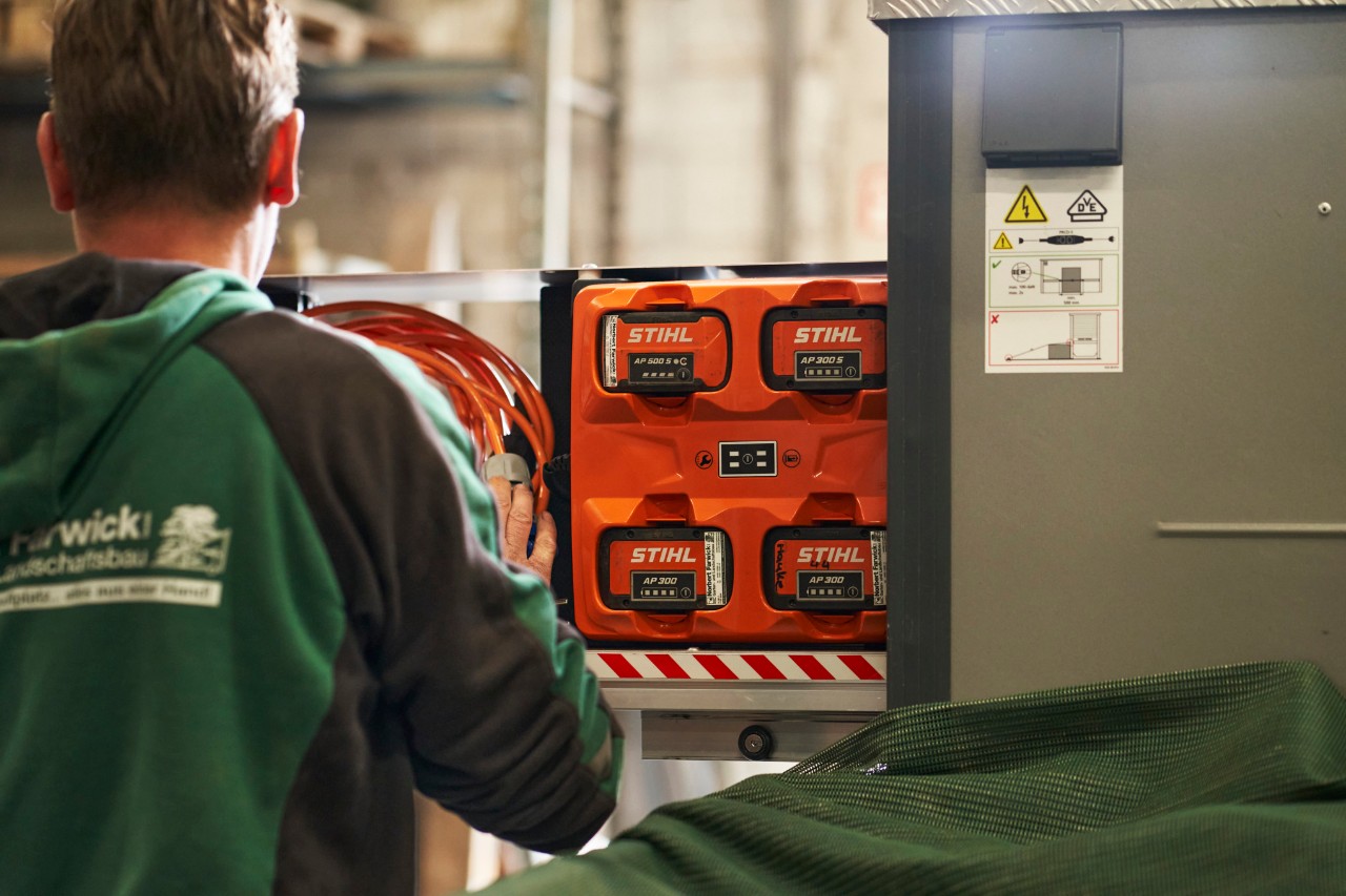 En medarbetare på Farwick GmbH med ryggen vänd mot kameran står framför en bottTainer powered by STIHL