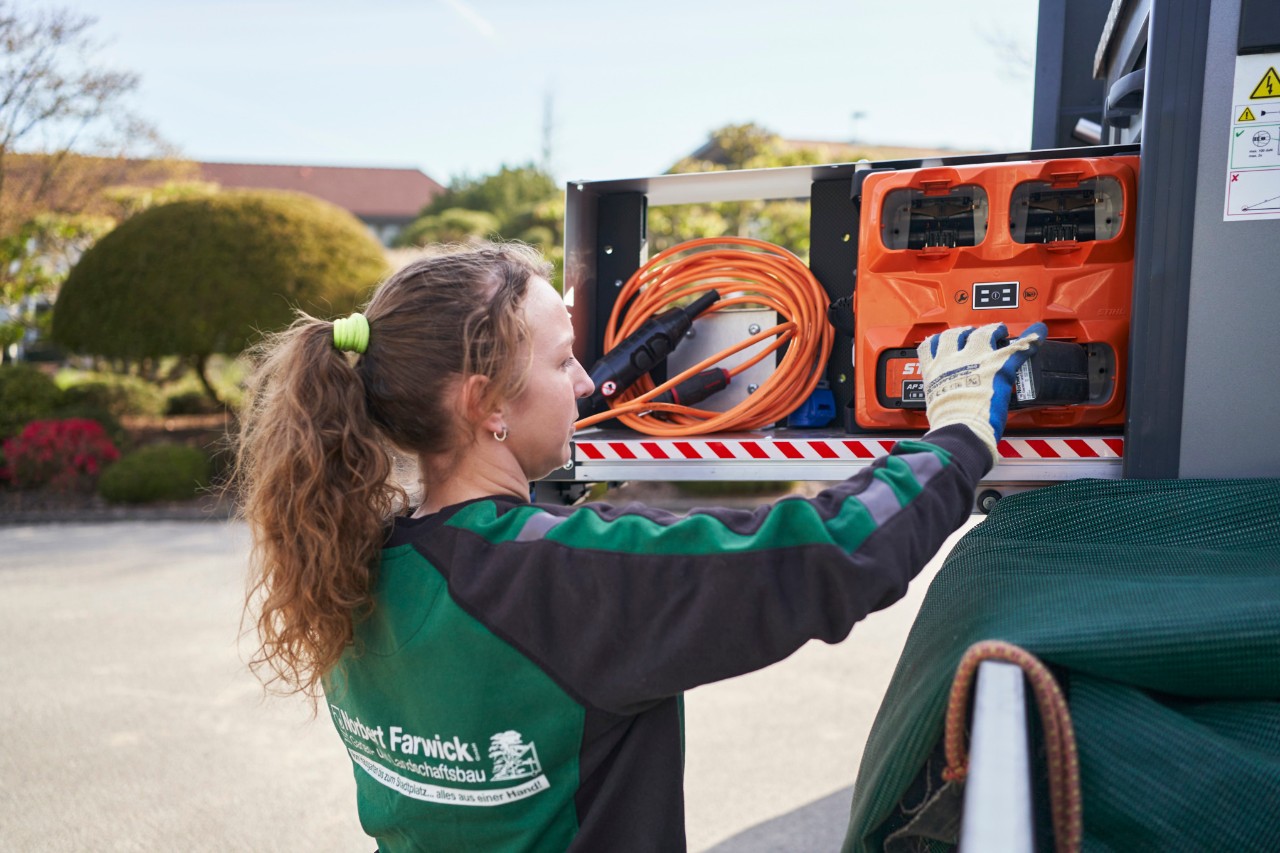 En medarbetare på Farwick GmbH lastar batterier i en bottTainer på ett utryckningsfordon