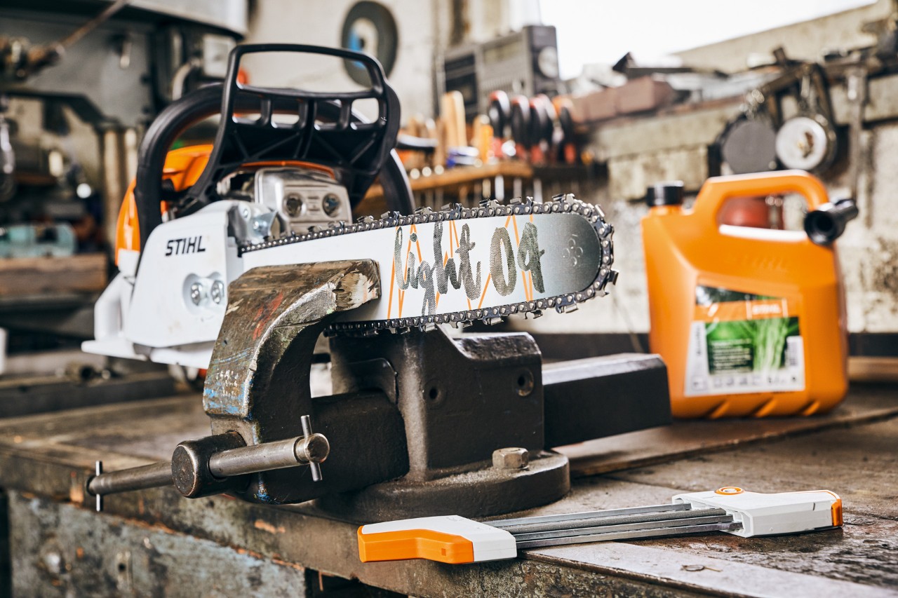 STIHL MS 261 C-M bensindriven motorsåg med svärd Light 04 bredvid STIHL MotoMix bränsleblandning före slipning