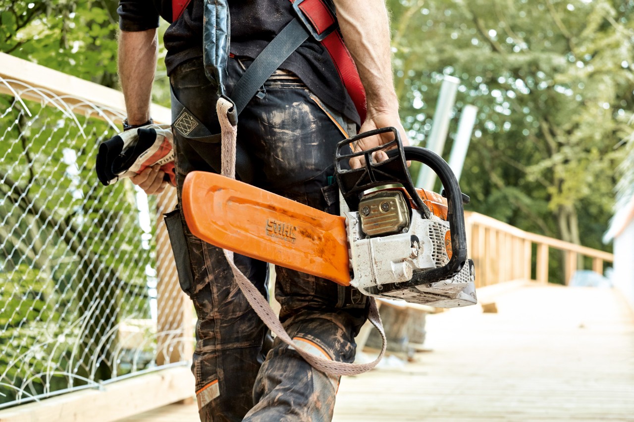  Man i skyddskläder bär en STIHL MS 261 bensindriven motorsåg med kedjeskydd