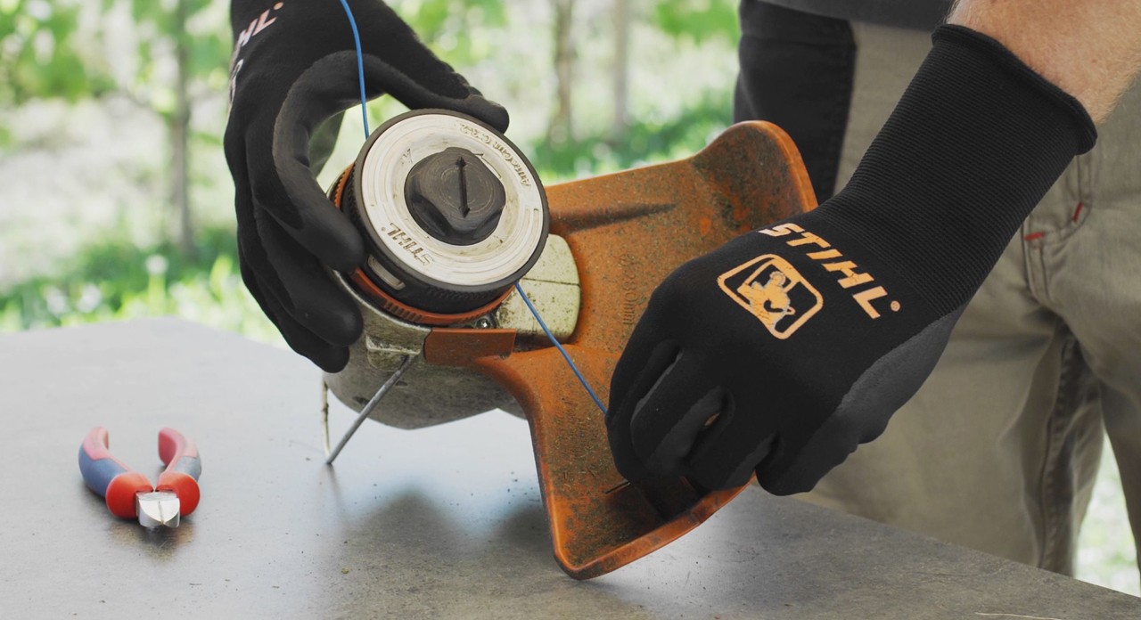En person lindar upp skärtråden på en STIHL batteridriven trimmer FSA 57