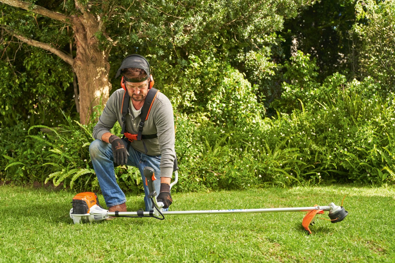 En man lägger STIHL FS 91 bensindriven trimmer på marken för att starta den