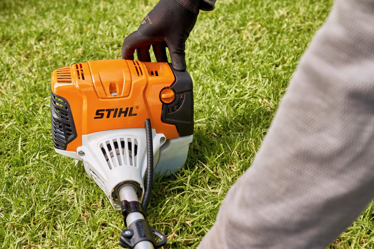 En man trycker STIHL FS 91 bensindriven trimmer mot marken