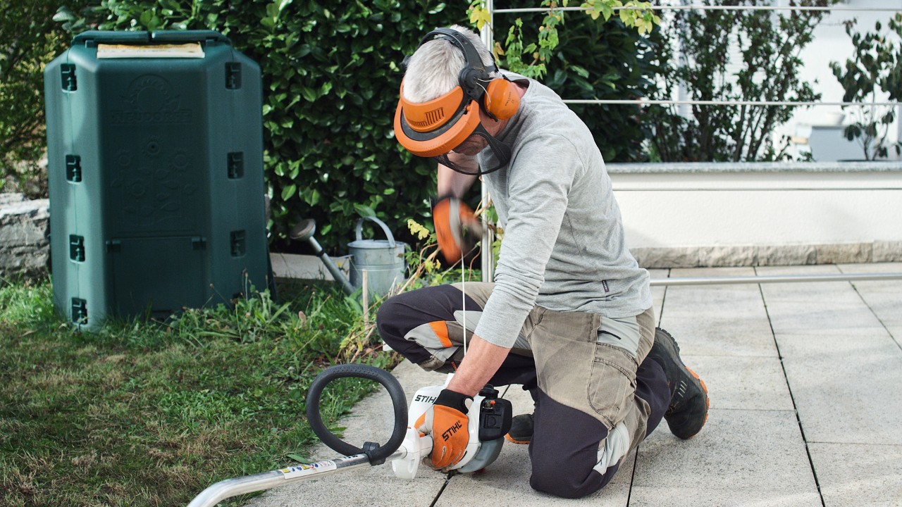 En person i skyddskläder drar i startsnöret på STIHL FS 38 bensindriven trimmer