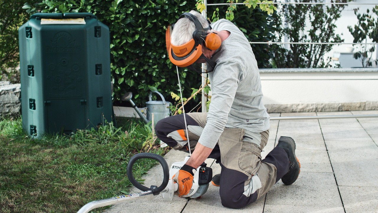 En person i skyddskläder drar på nytt i startsnöret på STIHL FS 38 bensindriven trimmer