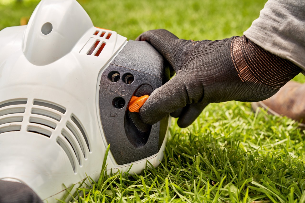 En man ställer in spaken på STIHL FS 56 bensindriven trimmer för att starta den