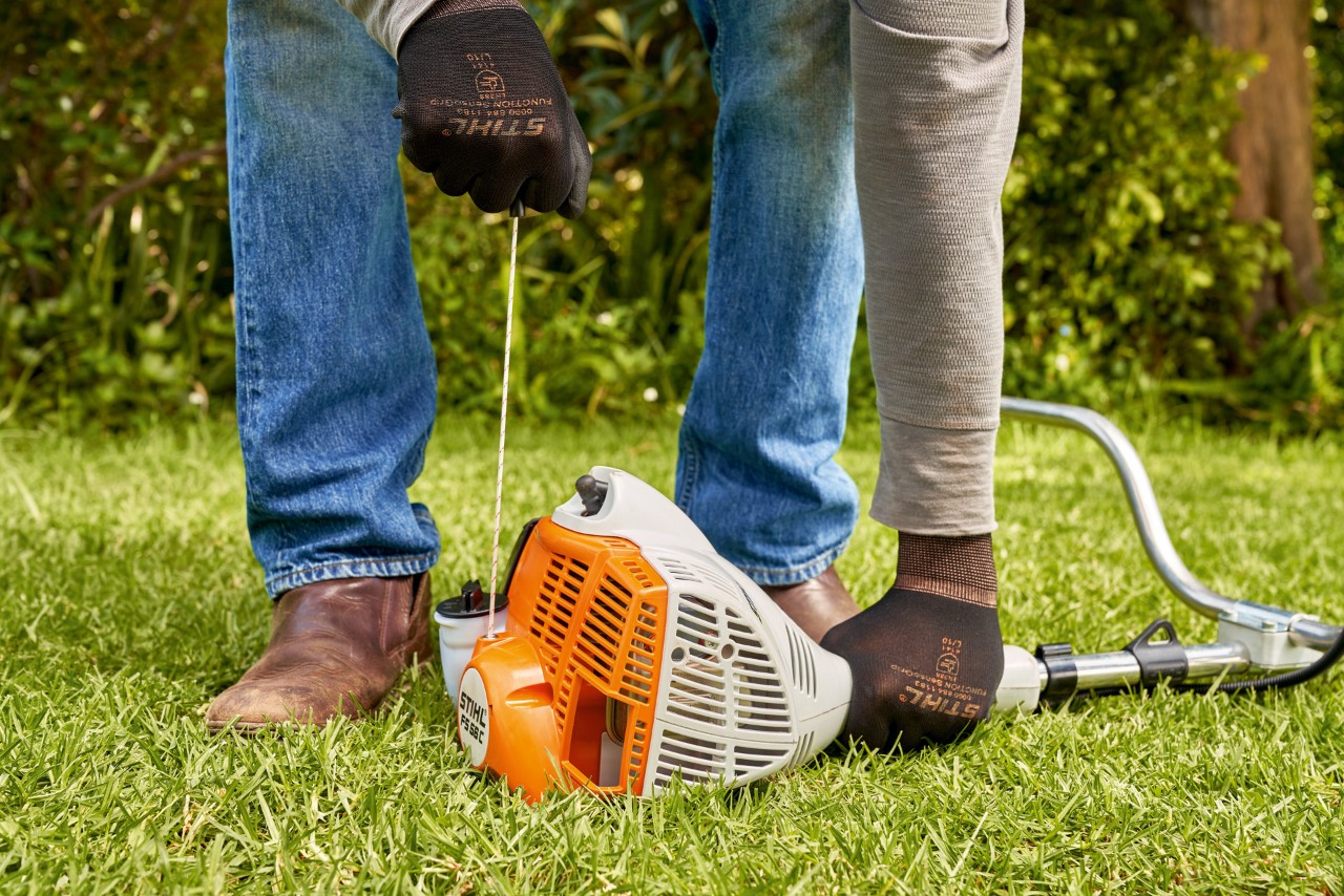 En man drar i startsnöret på STIHL FS 56 bensindriven trimmer 