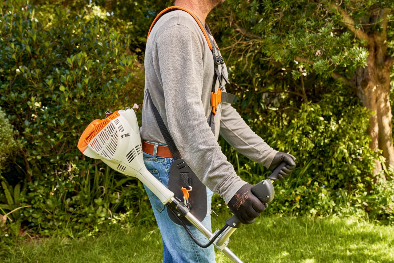 En man lyfter STIHL bensindriven trimmer FS 56 från marken