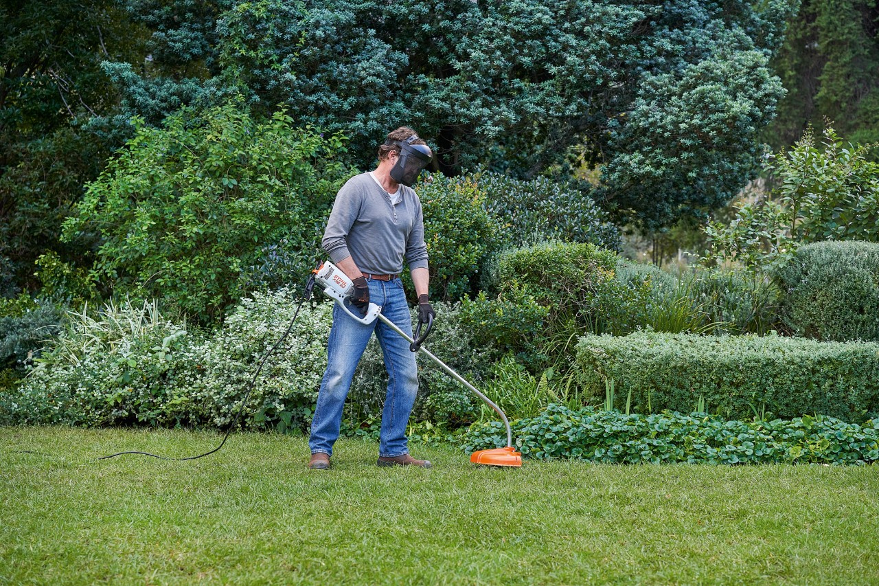 En man med STIHL FSE 60 elektrisk trimmer ställer sig stadigt