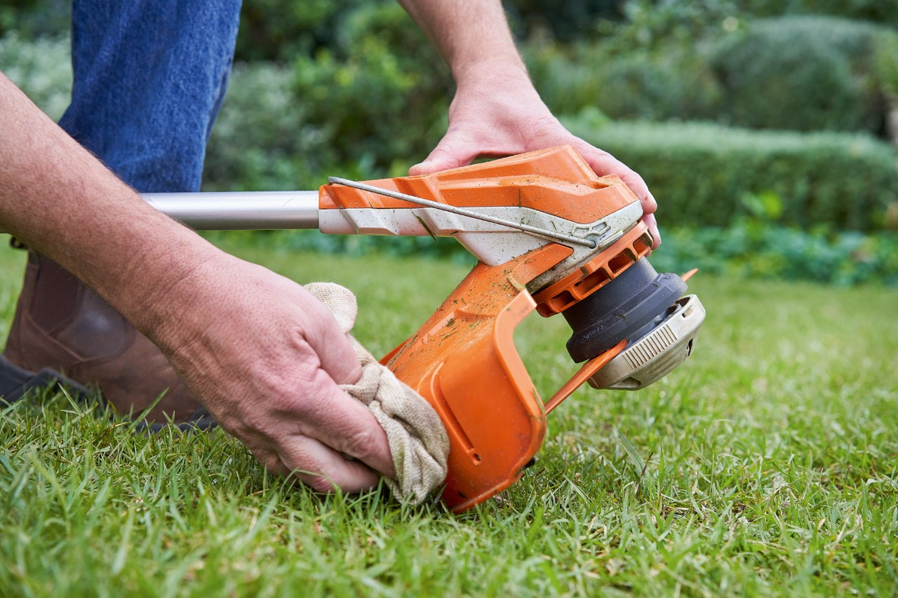 En person rengör skyddet på en STIHL timmer med en fuktig trasa