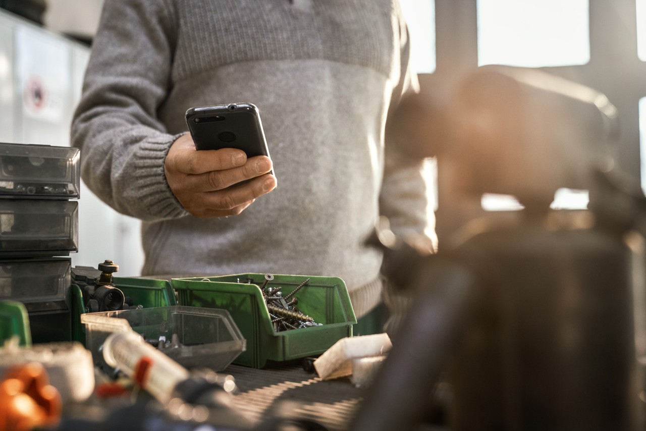En person med en smartphone i en verkstad