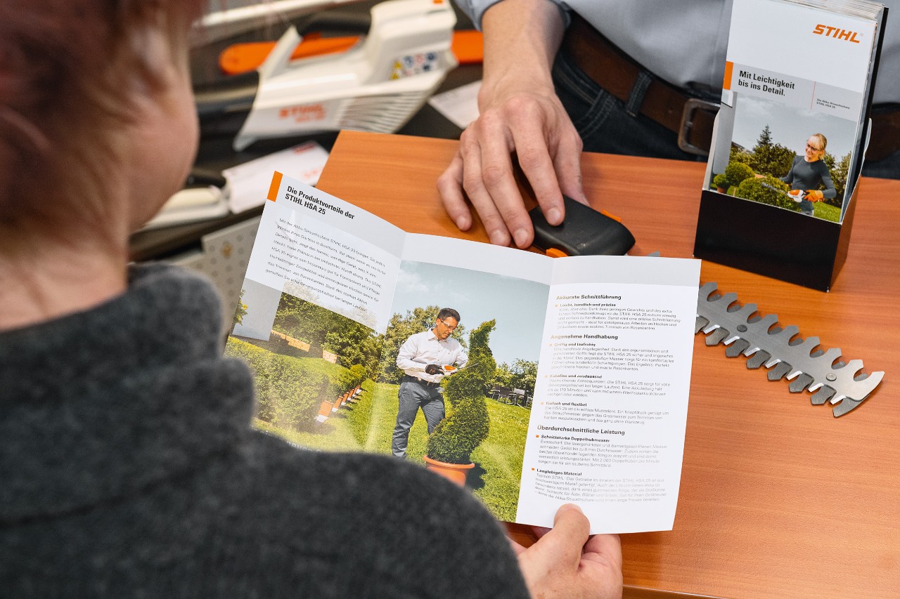 En person som läser om produktfördelarna med STIHL HSA 25 i en broschyr